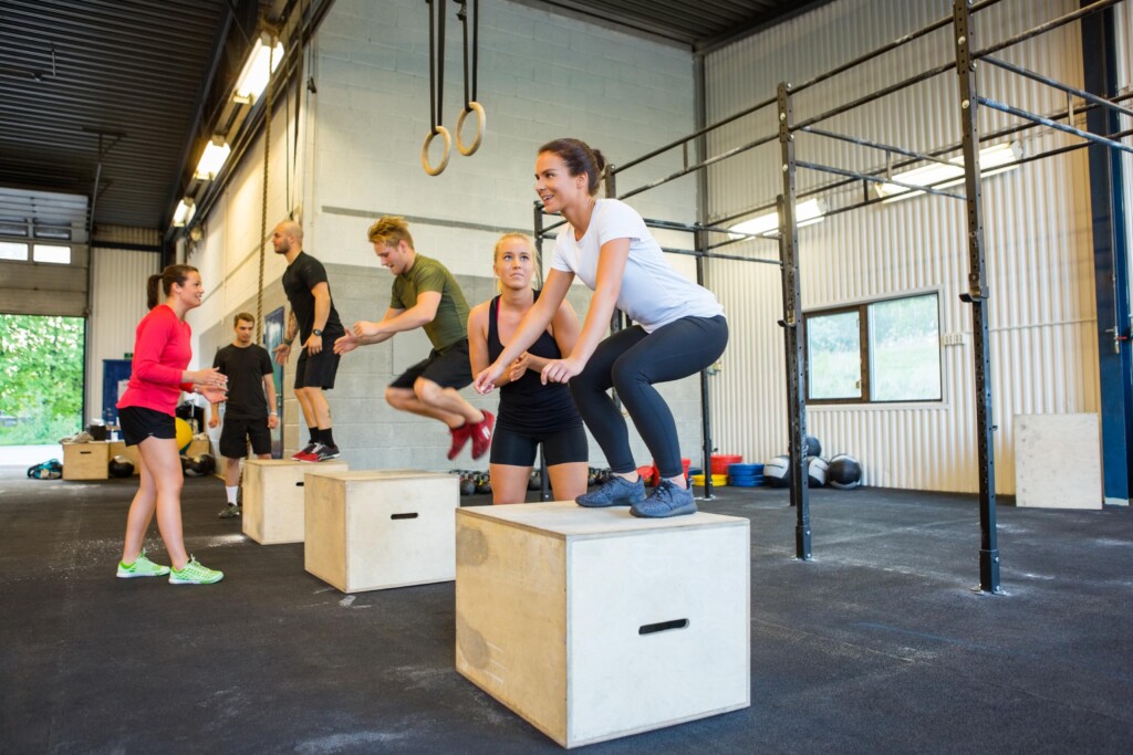 Group of athletes performing box jumps in a CrossFit gym